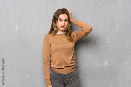 Teenager girl over textured wall with an expression of frustration and not understanding