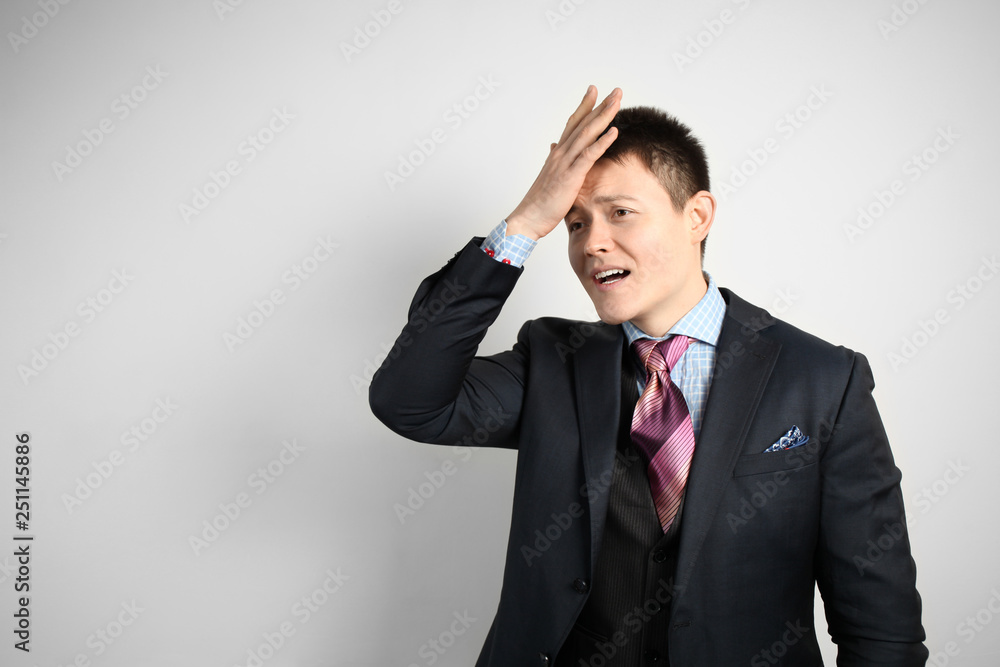 Young attractive businessman businessman in suit on gray background holding his head with his hand, mistake or surprise. Young attractive businessman businessman in suit on gray background holding his head with his hand, mistake or surprise.