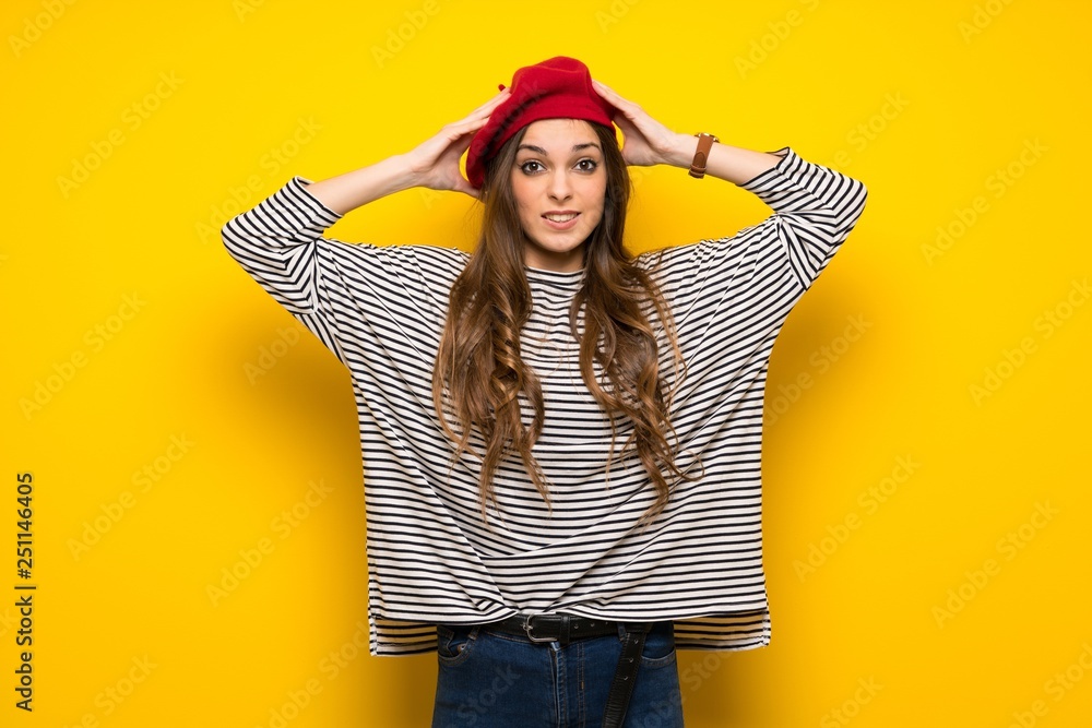 Girl with french style over yellow wall takes hands on head because has migraine Girl with french style over yellow wall takes hands on head because has migraine