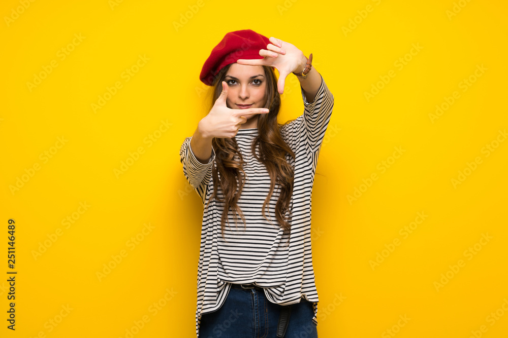 Girl with french style over yellow wall focusing face. Framing symbol Girl with french style over yellow wall focusing face. Framing symbol