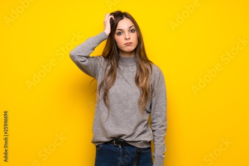 Young woman over yellow wall with an expression of frustration and not understanding © luismolinero