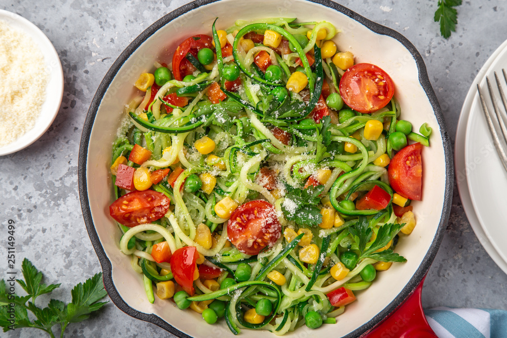 zucchini noodle with tomato, corn and green peas on pan, healthy vegan food