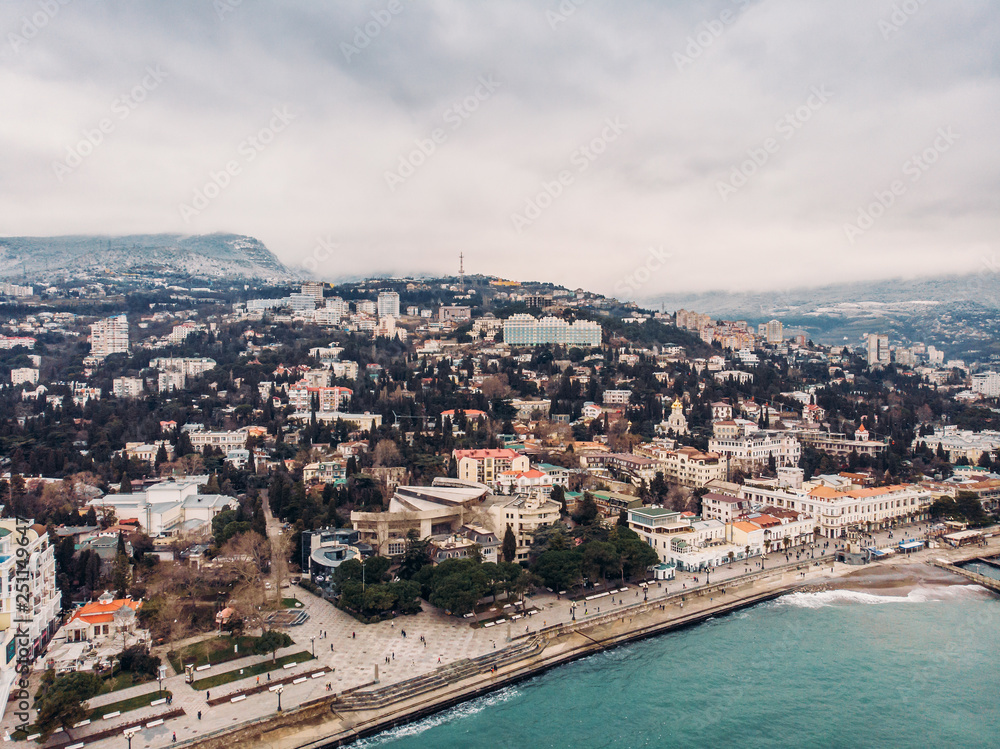 Aerial panoramic view of Yalta city embankment with sea, mountains and breakwaters, beautiful resort for vacation