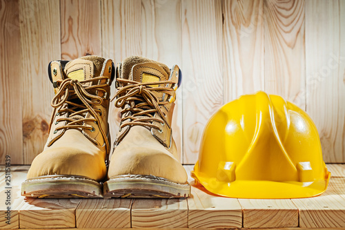 working boots and yellow helmet on wood background