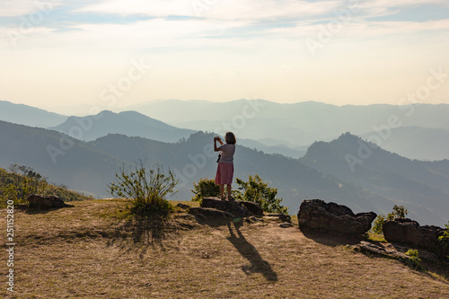 Asian tourist  taking photo from top of the mountain with valley view of Doi Pha Tang Chiang Rai. photo