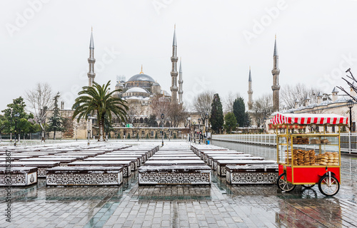 Snowy day in Sultanahmet Square. Blue Mosque (Sultanahmet Camii) and Turkish Bagel Seller. Istanbul, Turkey..