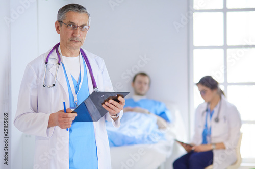 Doctor holding folder in front of a patient and a doctor