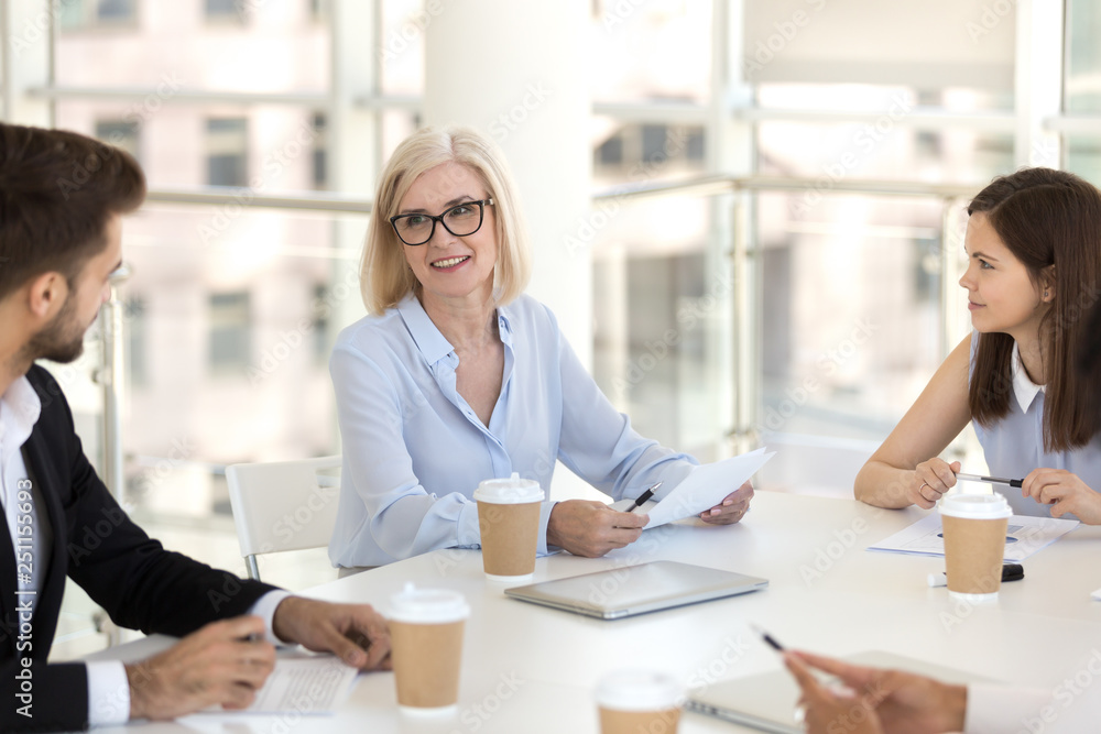 Mature team leader sitting with colleagues at briefing Mature team leader sitting with colleagues at briefing