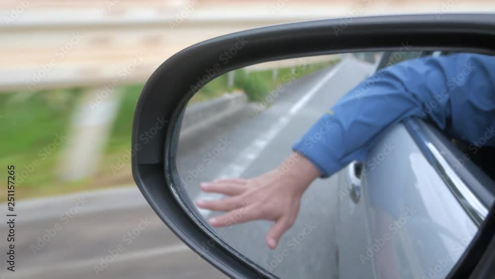 Hand waving outside the car while moving with landscape natural view of the okinawa island in Japan Hand waving outside the car while moving with landscape natural view of the okinawa island in Japan