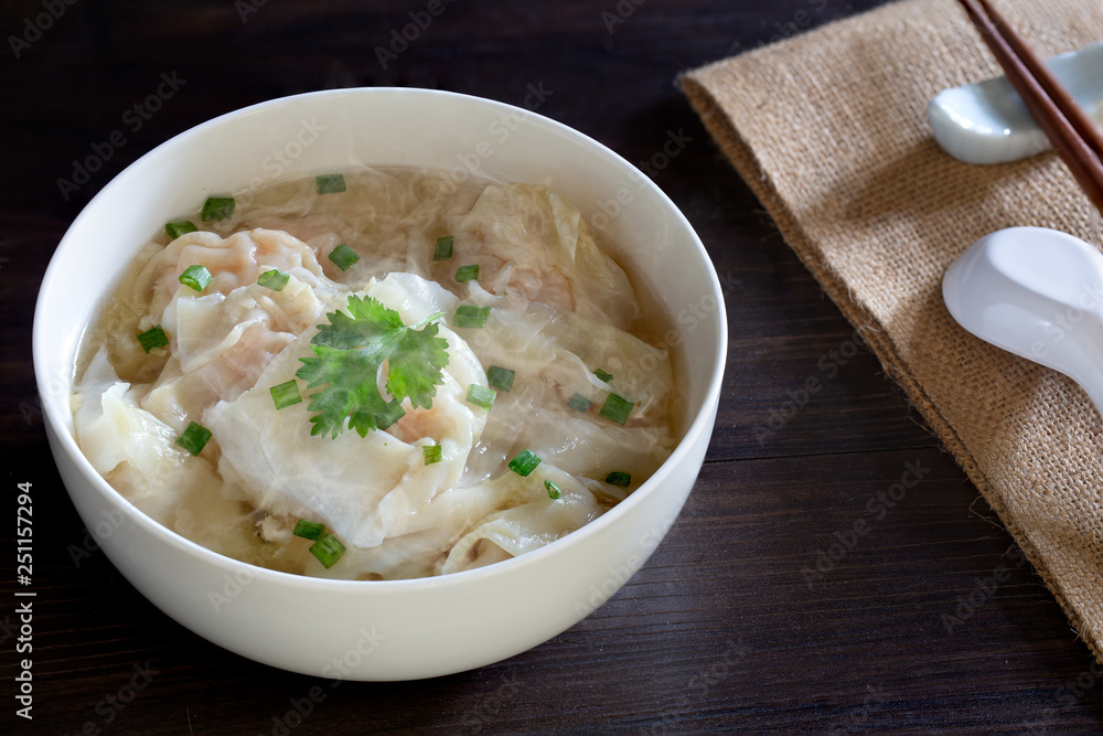 Shrimp wonton in hot soup in white bowl on dark wooden table, Asia food Shrimp wonton in hot soup in white bowl on dark wooden table, Asia food