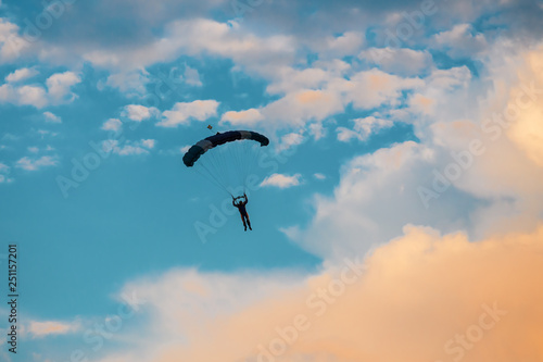 Parachutist falling from the sky in evening sunset dramatic sky. Recreational sport  Paratrooper silhouette on colored sky.
