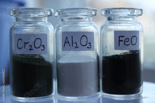 Photos Metal oxides in glass jars: dark green chromium oxide, white aluminium oxide, black iron oxide