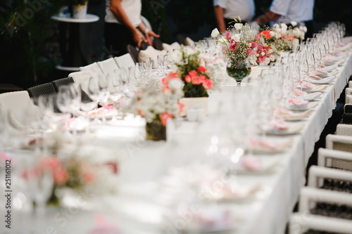 Bouquets of flowers and crystal dishes decorated on a white table.