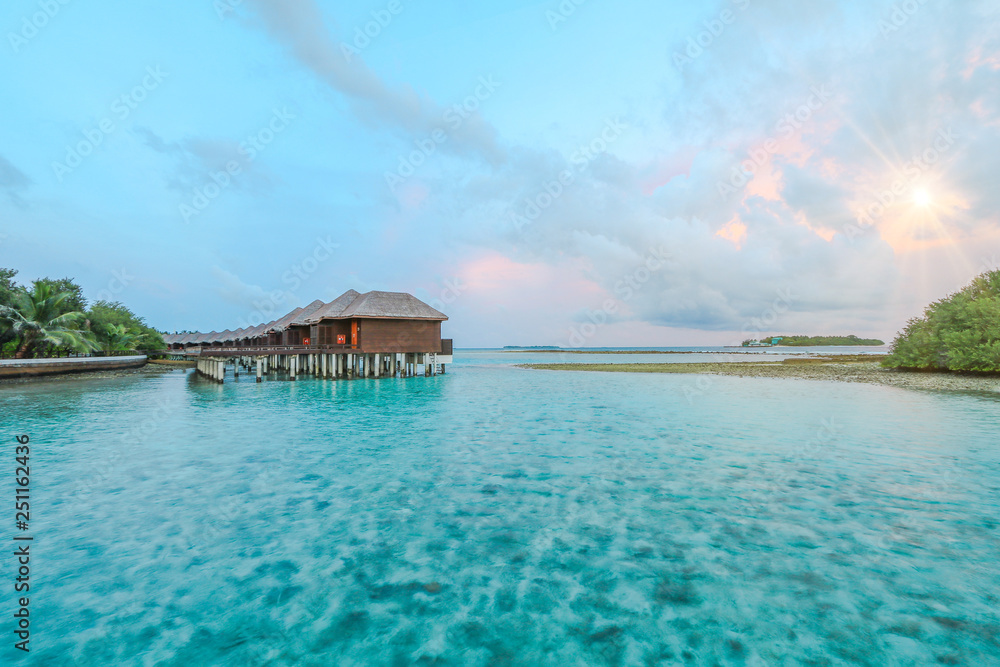 Amazing island in the Maldives ,water villa ,wooden bridge and beautiful turquoise waters with sunrise background for holiday ,summer, vacation .
