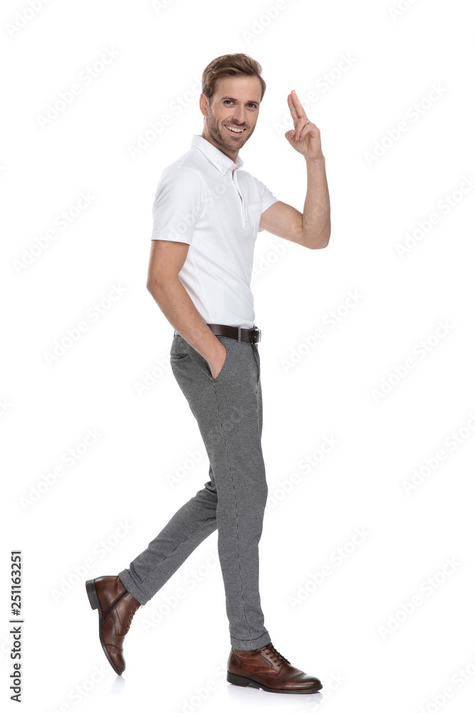 smiling casual man with hand in pocket walks and salutes smiling casual man with hand in pocket walks and salutes