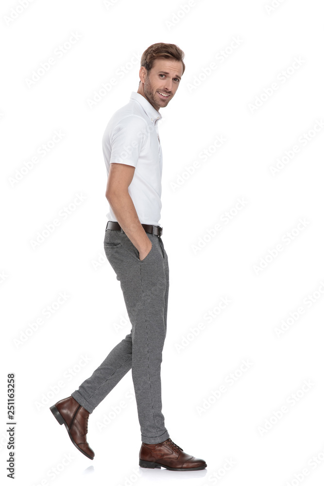 side view of a relaxed young smart casual man walking