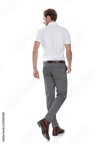 back view of a walking casual man looking to side