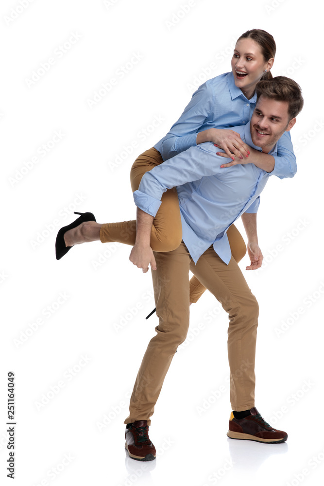young man carries woman on his back looking to side