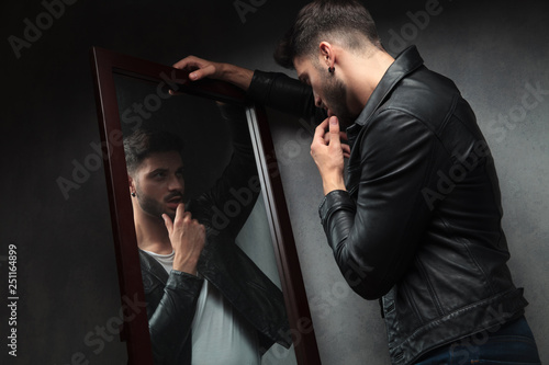 narcissist sexy young man admiring himself in the mirror photo