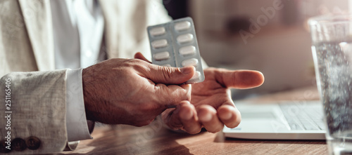 Businessman taking medical pills in the office photo