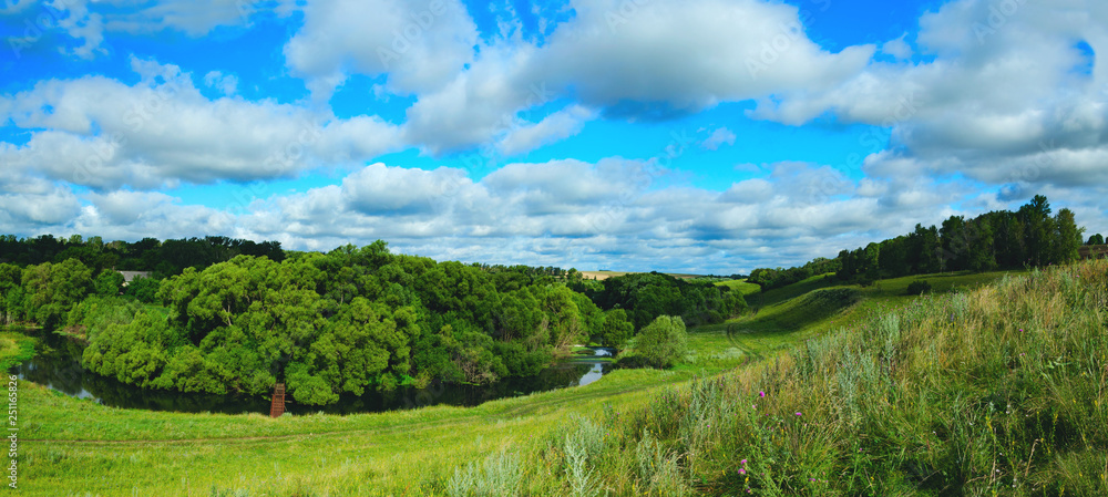 Sunny summer country landscape with river bend and green hills with growing trees