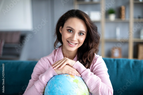 Portrait happy woman planning a trip or summer vacation with globe of the world smiling.