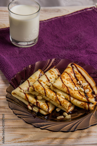 Three pancakes on a plate with chocolate sauce