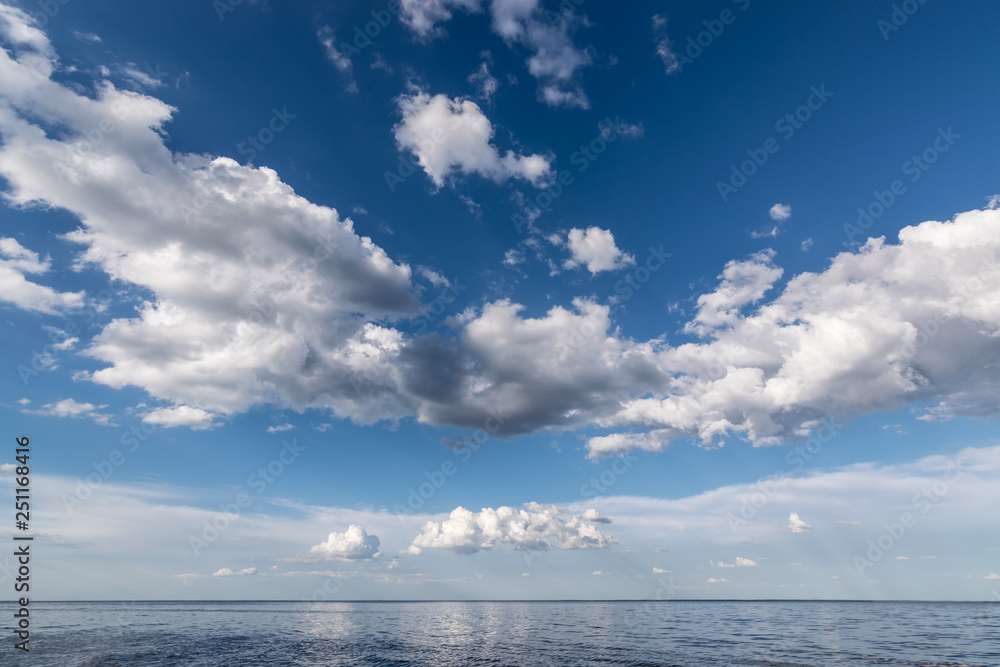 White clouds in the blue sky above the water