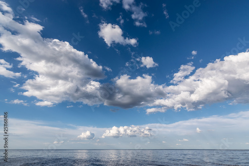 White clouds in the blue sky above the water