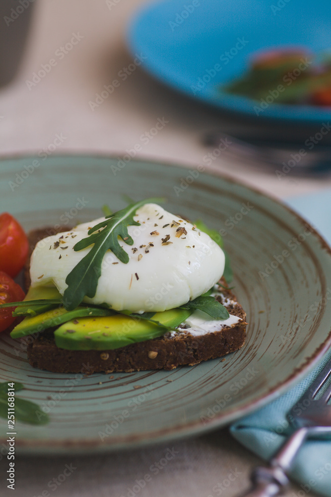 sandwich with avocado, poached egg, arugula and cherry tomatoes