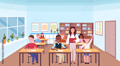 woman teacher reading book during lesson mix race pupils sitting desks education concept modern school classroom interior horizontal flat