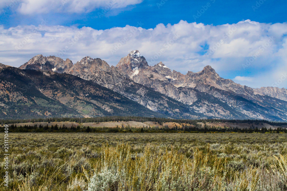 Majestic Grand Teton Mountains with beautiful blue skies and bright white fluffy clouds