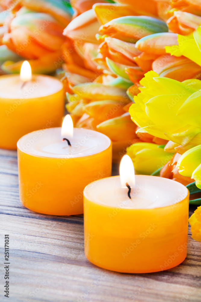 Tulips and daffodils with candle against wooden background Tulips and daffodils with candle against wooden background