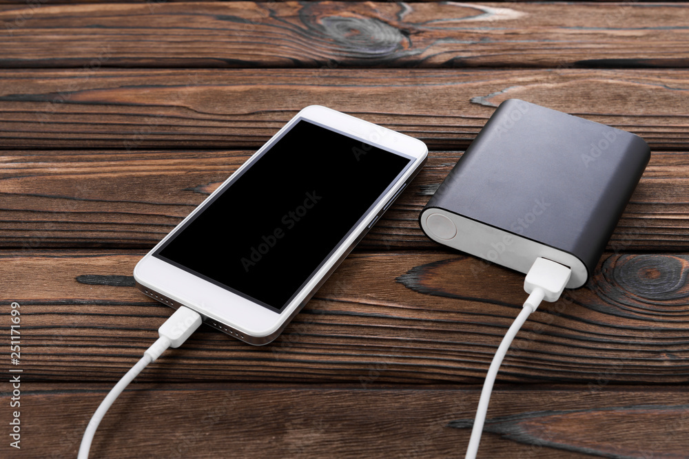 smartphone with black screen, portable charger on wooden table background. Technologies. smartphone with black screen, portable charger on wooden table background. Technologies.