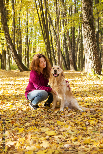 Beautiful woman with a golden retriever dog in autumn park