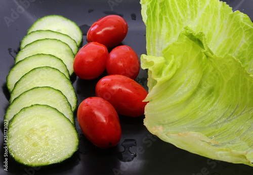 Cucumber slices, cherry tomotoes and lettuces leaves for summer salad. photo