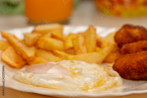 A fried country egg with potatoes and homemade croquettes