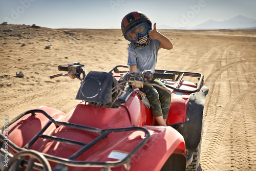 Kid in helmet and protect mask riding quad bike