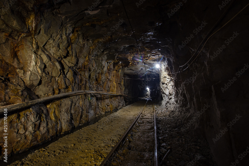 Naklejka premium Underground gold ore mine shaft tunnel gallery passage with rails and light