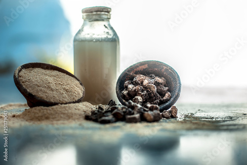 Popular Indian & Asian ayurvedic organic herb musli or Chlorophytum borivilianum or Curculigo orchioides or kali moosli in a clay on wooden surface with a transparent glass bottle filled with milk. photo