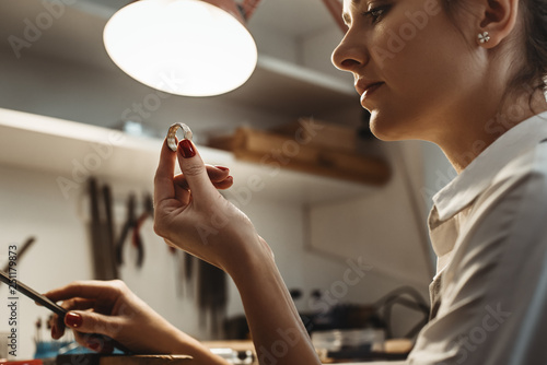 Perfection. Close up of young female jeweler looking and inspecting a ring. photo