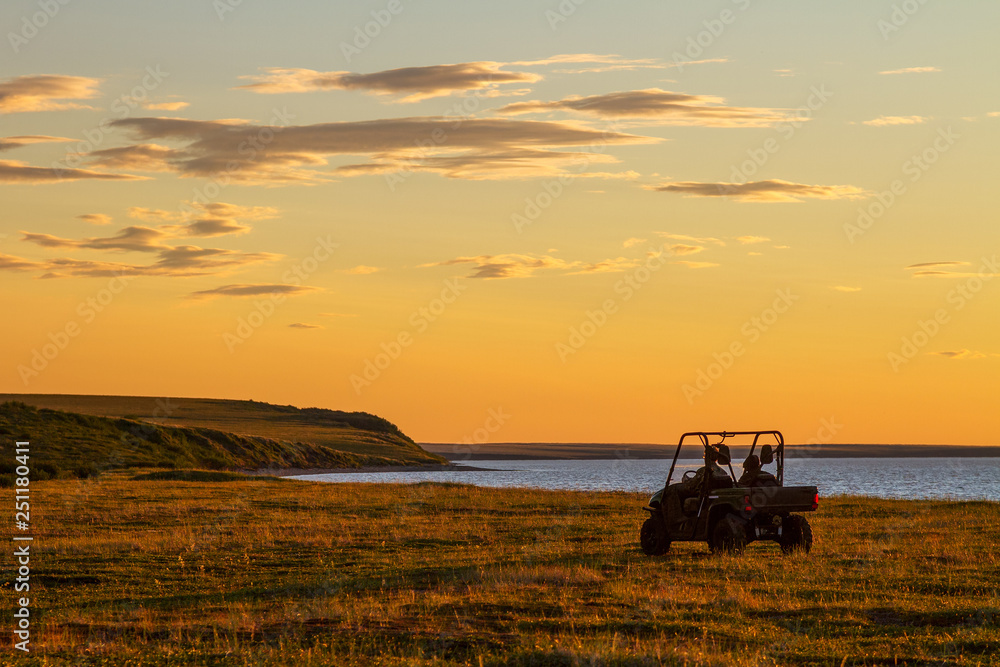 Utility terrain vehicle (UTV, quad bike or buggy car) in the tundra. Beautiful summer sunset in the extreme North. Off-road trip in the Arctic. Adventure tourism. Chukotka, Siberia, Far East of Russia