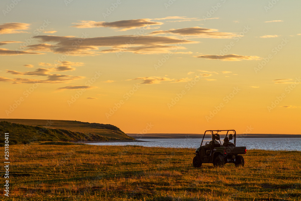 Utility terrain vehicle (UTV, quad bike or buggy car) in the tundra. Beautiful summer sunset in the extreme North. Off-road trip in the Arctic. Adventure tourism. Chukotka, Siberia, Far East of Russia Utility terrain vehicle (UTV, quad bike or buggy car) in the tundra. Beautiful summer sunset in the extreme North. Off-road trip in the Arctic. Adventure tourism. Chukotka, Siberia, Far East of Russia