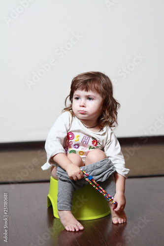 a little girl sits on a potty and makes funny faces