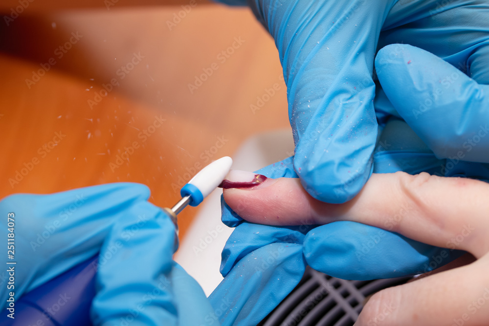 Manicure process close-up. Removing old decorative nail polish with a milling machine