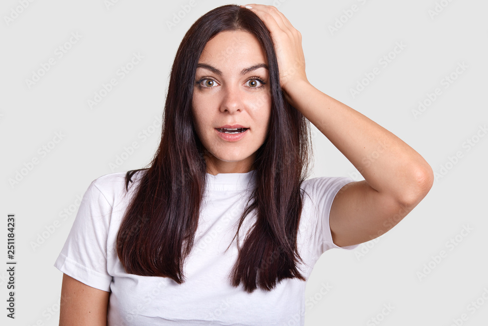 Pretty brunette female with wide open mouth in portrait photo poses for photographer who asks to show different situations. Model stands on isolated gray background and looks into center of lens. Pretty brunette female with wide open mouth in portrait photo poses for photographer who asks to show different situations. Model stands on isolated gray background and looks into center of lens.