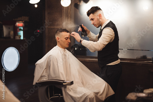 Professional barber splashes water on a client head in barbershop salon