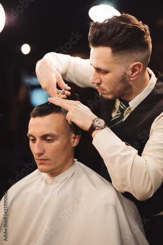 Professional haircut with scissor in a male barbershop salon