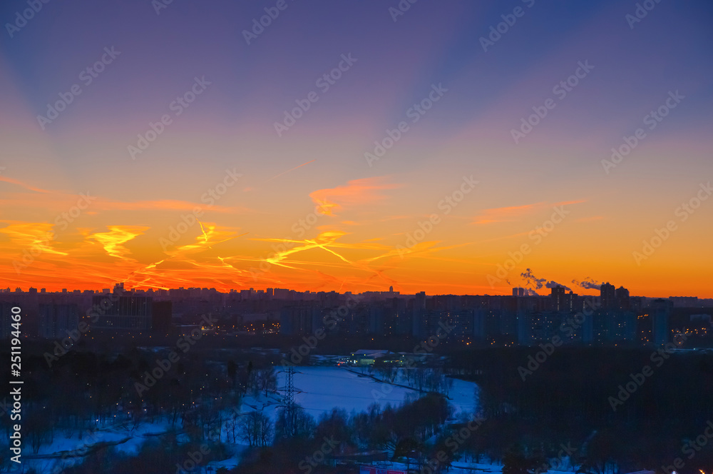 Orange clouds with aircraft trails sky background and city light midnight evening time