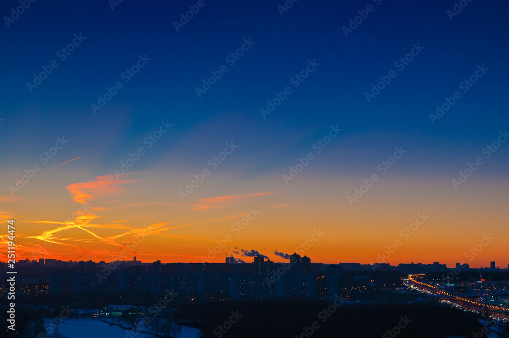 Orange clouds with aircraft trails sky background and city light midnight evening time